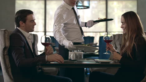 pareja feliz brindando con un vaso de vino tinto en un restaurante
