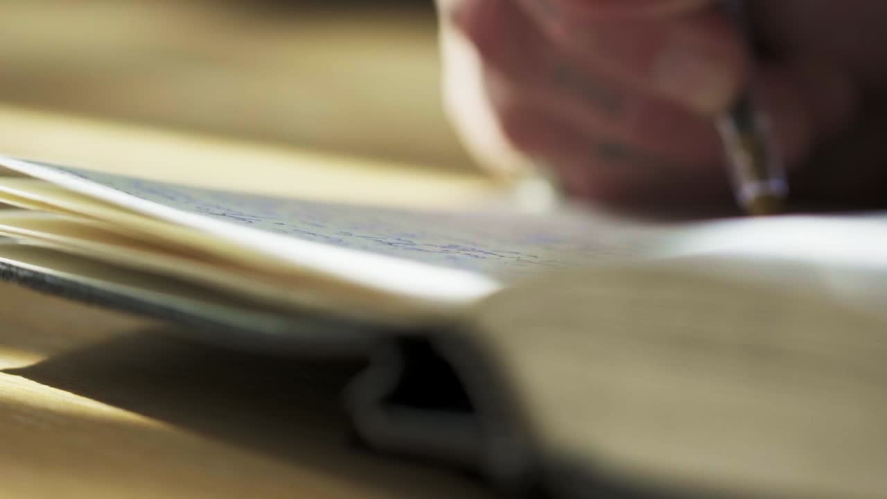 movimiento lento de la mano escribiendo notas en papel de cuaderno con tinta pluma sol diario desarrollo personal meditativo