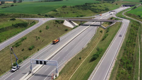aerial view of a highway with twin tunnels and an overpass surrounded by green fields