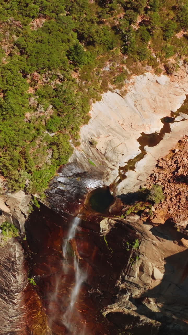 Tiny waterfall in the mountains of Yosemite, California, USA. High rock cliff with a creek falling down. Sunny day footage from top. Vertical video