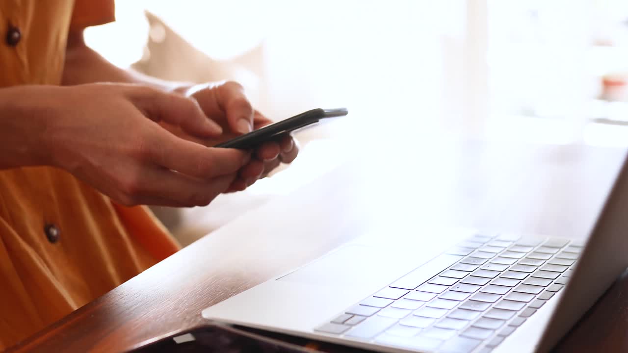 Donna caucasica che usa un laptop e il telefono a casa.