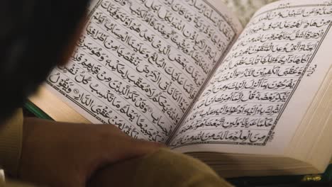 close up of muslim man at home sitting on floor and reciting from the quran 1