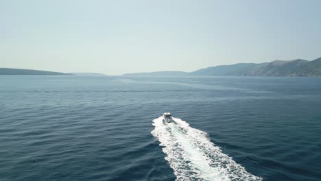 a boat speeds through the calm blue sea leaving a white wake behind