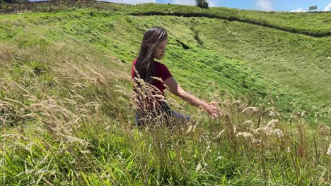 beautiful brunette woman sitting in long grass on hill overlooking lagoon in costa rica, 4k