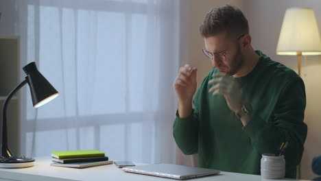 hombre agotado está trabajando con la computadora portátil por la noche cerrando el cuaderno y apagando la lámpara de mesa frotando ojos cansados y templos trabajo duro con la pc