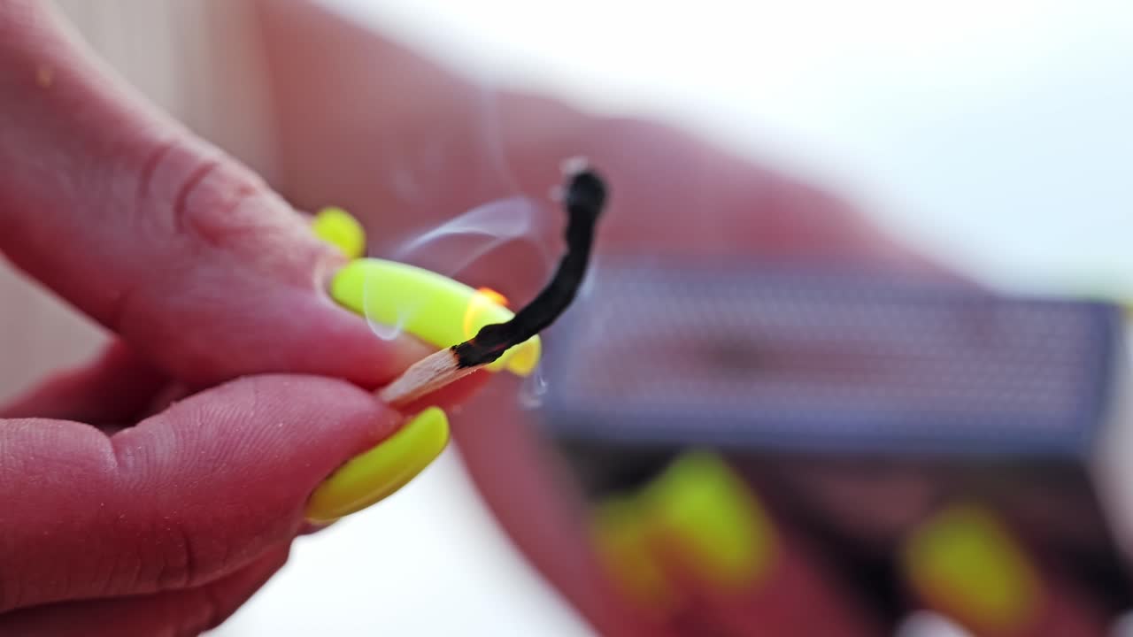 Matchstick slowly burns out in close-up, smoke curling in calm air around