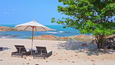 Sun-umbrella-and-two-deckchairs-on-rocky-beach-with-sea-in-background