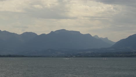 Panoramic-Time-Lapse-boats-sailing-at-Lake-Bourget-french-mountain-skyline-clouds-in-motion-at-Ailx-Les-Bains,-european-spa-travel-destination