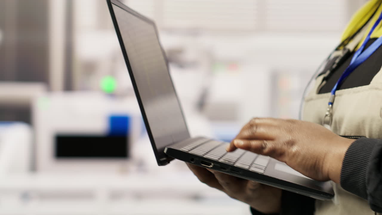 Vertical video Technician in industrial plant monitors production equipment using laptop