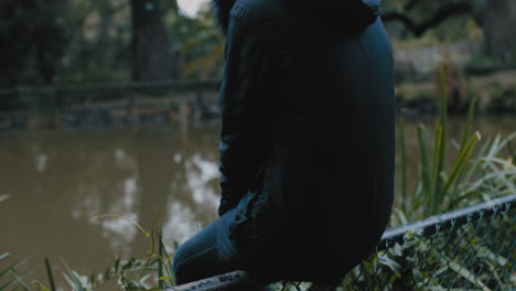 young woman sitting alone in park enjoying peaceful nature pond lonely teenage girl feeling depressed on cold cloudy day