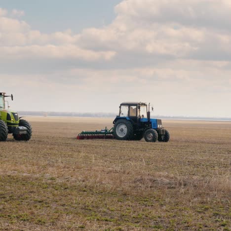 steadicam shot: two tractors with seeders sow wheat on the field in early spring