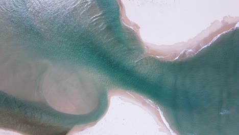 Lagoon-estuary-mouth-opens-up-to-the-ocean-as-the-tide-pushes-in-with-sand-sediment-formation-visible