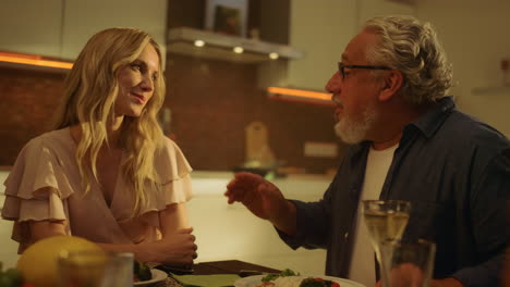 Smiling-family-talking-together-during-dinner-in-kitchen