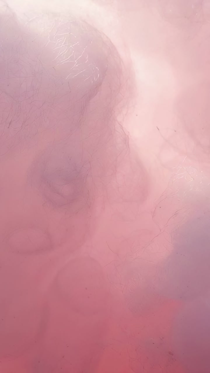 Vertical video: Shifting macro camera revealing skin patch with lint, hairs to show fibers at home