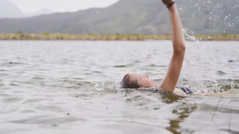 Caucasian-woman-having-a-good-time-on-a-trip-to-the-mountains,-wearing-bathing-suit-and-swimming-in-