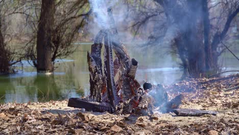 bonfire burning on the river bank, bright sunny day, beautiful nature, travel, hiking and camping concept