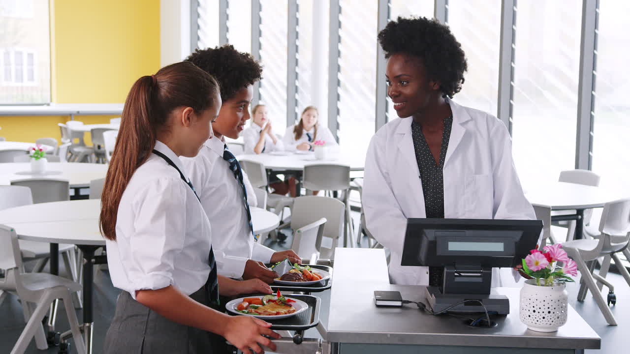 estudiantes de secundaria con uniforme pagando por la comida en la cafetería
