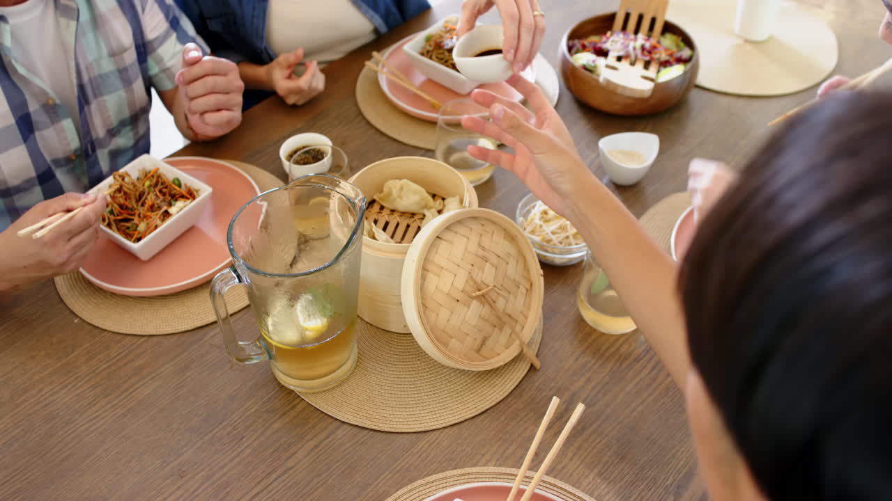 Eating Asian cuisine, family sharing food at dining table, enjoying meal together