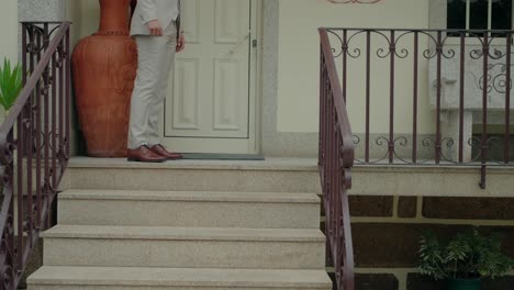 man in beige suit and brown shoes walking down stone stairs with large terracotta vase