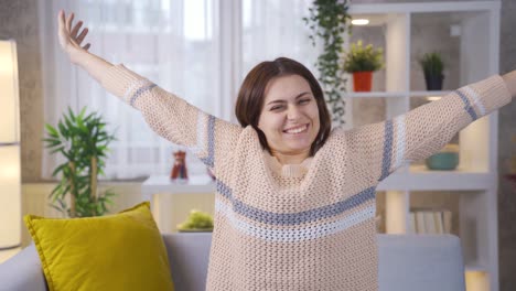 Happy-and-relaxed-young-woman-at-home,-young-woman-waving-at-camera-in-a-good-mood.