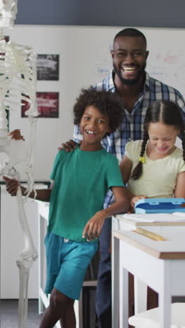 video of happy african american teacher with class of diverse pupils during anatomy lesson