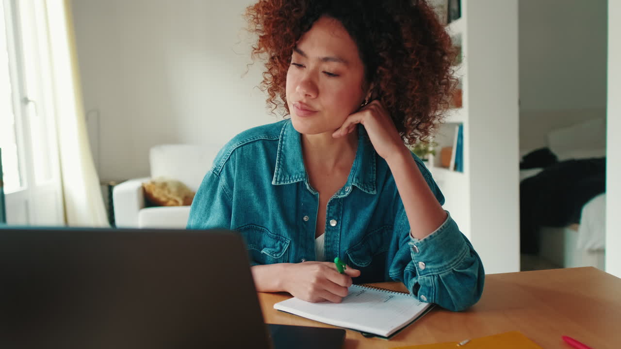 Young Woman Writing Notes and Talking During Online Class