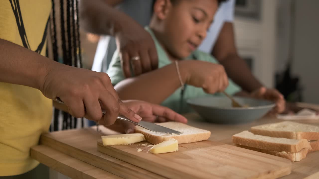 Family preparing breakfast, close-up of hands spreading butter on bread