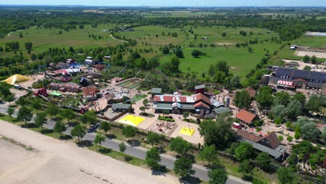 amusement park with roller coasters, various attractions, and green spaces in germany. speed ramp hyper motion time lapse. magic aerial view flight descending drone