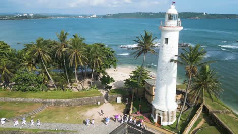 paradise beach with palm trees in sri lanka with the white lighthouse of galle dutch fort