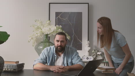 a bearded man holds on to a woman's anger while looking at the camera