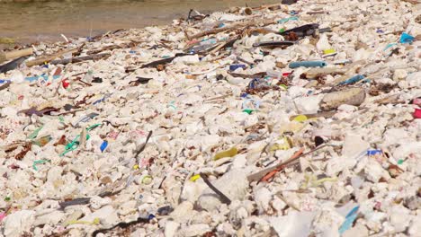 Static-tripod-of-man-made-plastic-debris-and-rubbish-slowly-being-washed-up-on-rocky-shore-in-the-Caribbean