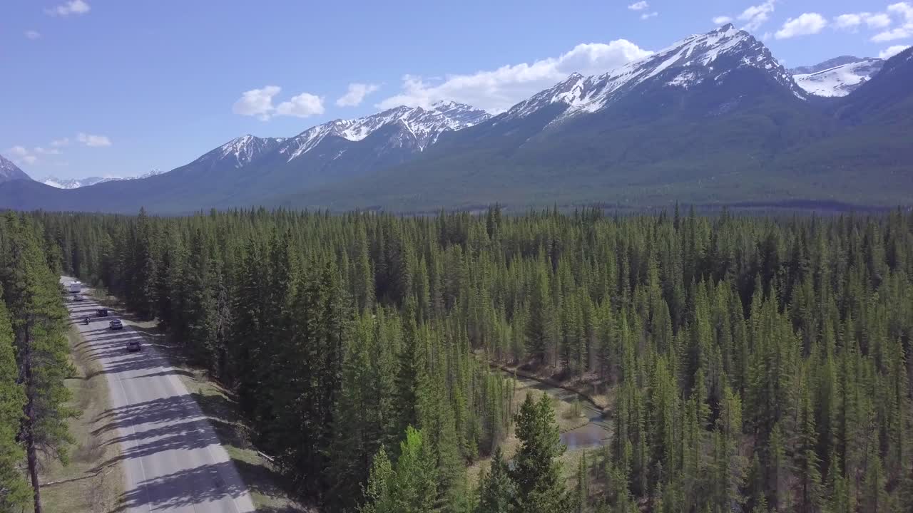 vista aérea sobre el tráfico que viaja bosque canadiense hacia la cordillera cubierta de nieve
