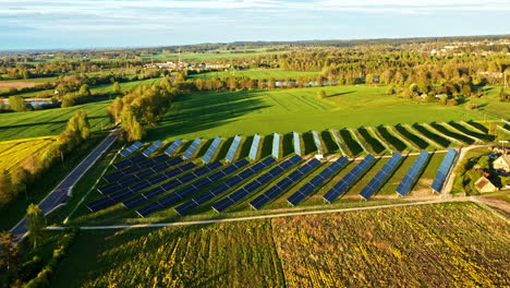 drone view of large modern solar panel farm in countryside surrounded by green fields