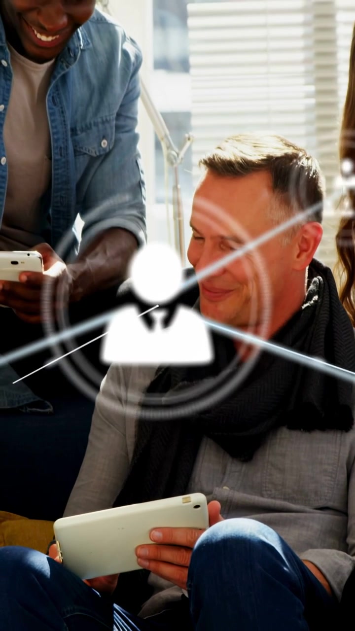 Vertikální video: Sedící muž ukazuje telefon kolegovi na tabletu, jiskřící síť se šíří pro technický tým.