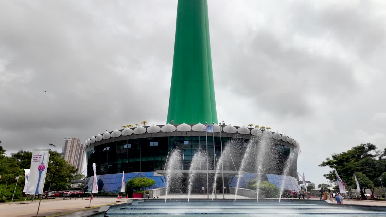 View of fountains gracefully dancing in front of Colombo Lotus Tower on a cloudy day in Sri Lanka. The iconic architectural landmark stands tall, showcasing its impressive modern design.
