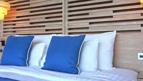 hotel king-size made-up bed with blue and white pillows and turned on night lamps lights, handheld pan