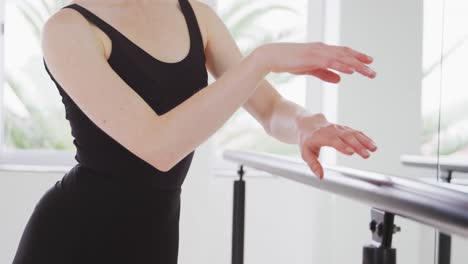 caucasian female ballet dancer practicing up by the mirror for dance class in a bright studio