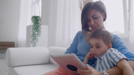 madre y hijo jugando con una tableta digital en casa. madre joven con su hijo de 5 años sonriendo con una tablet digital en casa