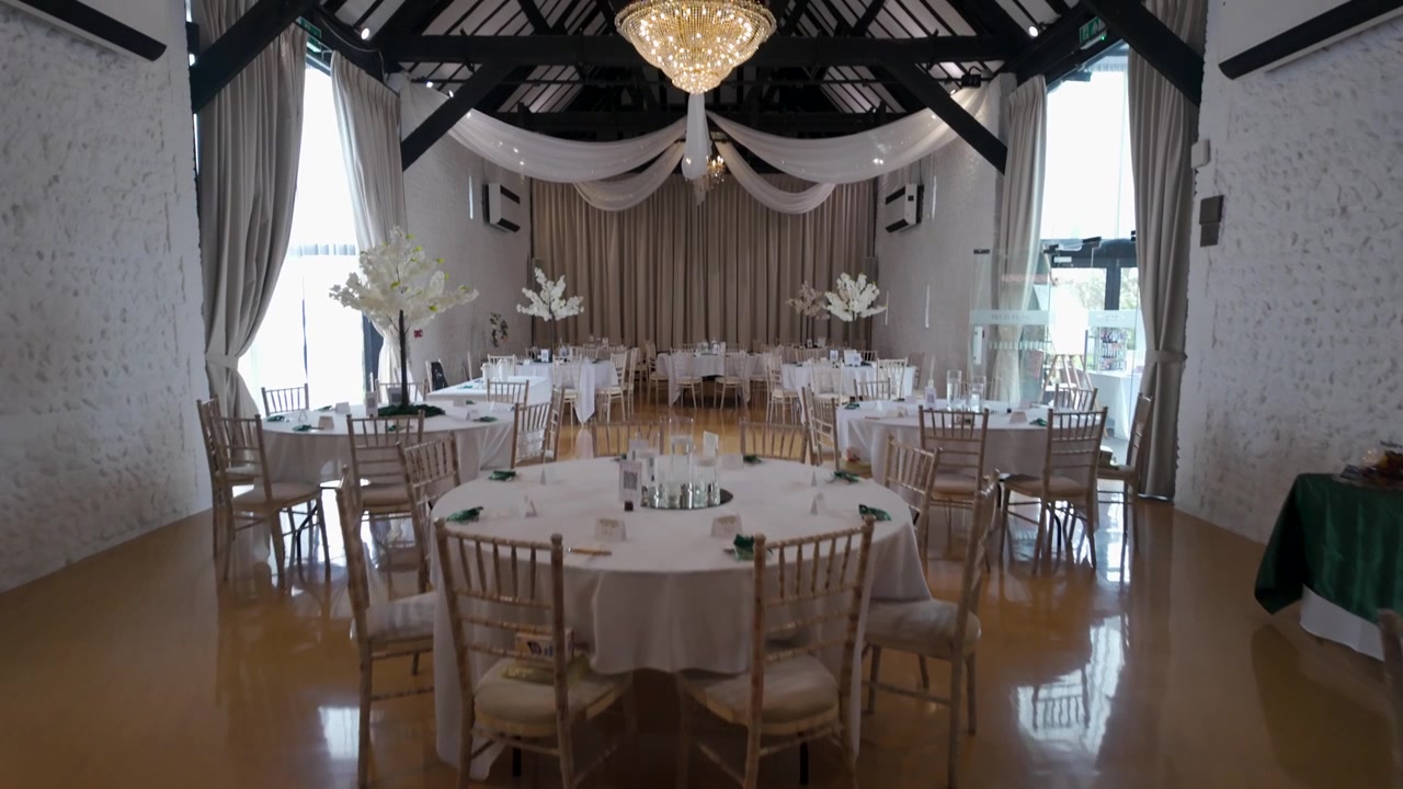 Dolly forward tilt up revealing crystal chandelier in elegant wedding venue