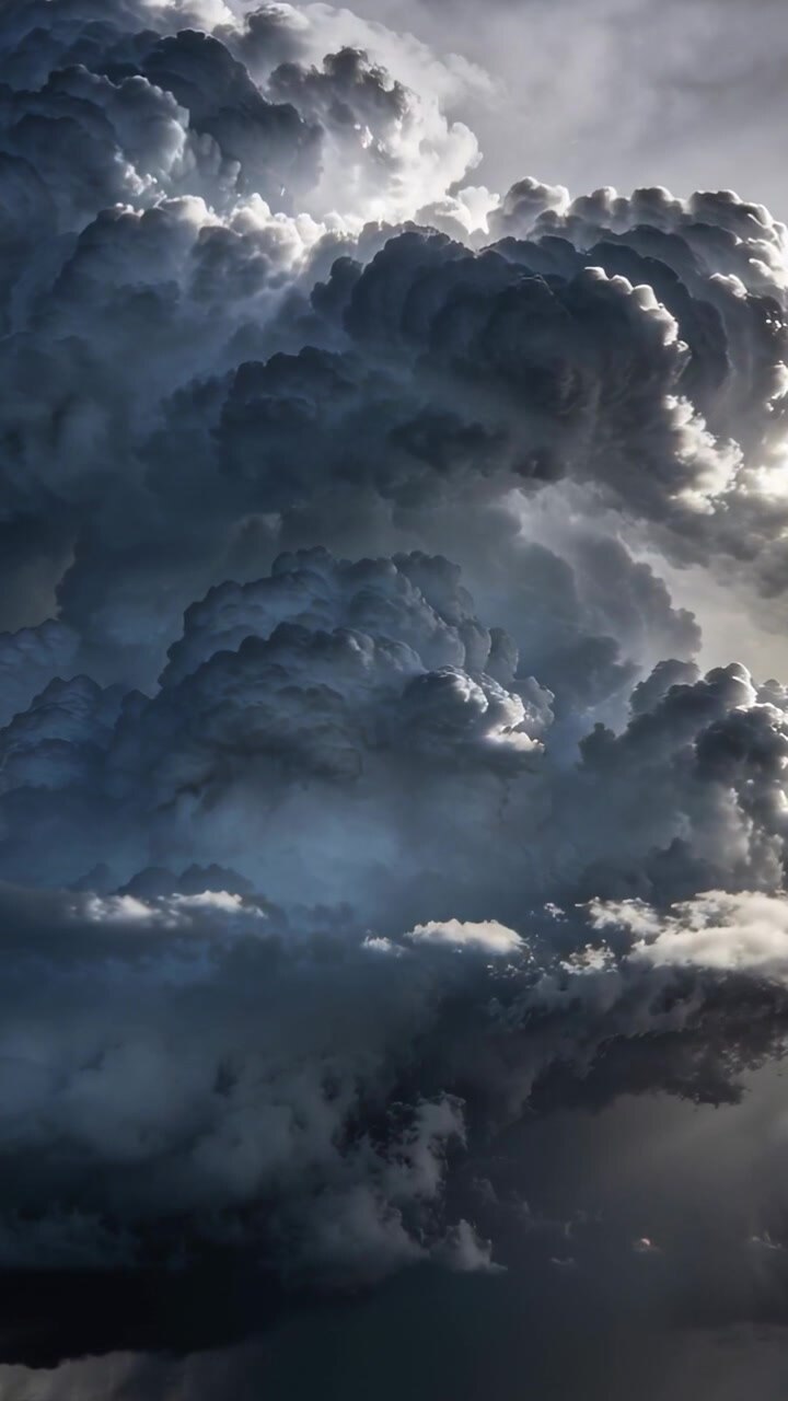 Video verticale: Nuvola cumulonembo in formazione che sale per convezione nel cielo, con il sole che retroillumina le sue torri.