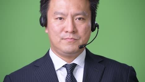 mature japanese businessman against green background