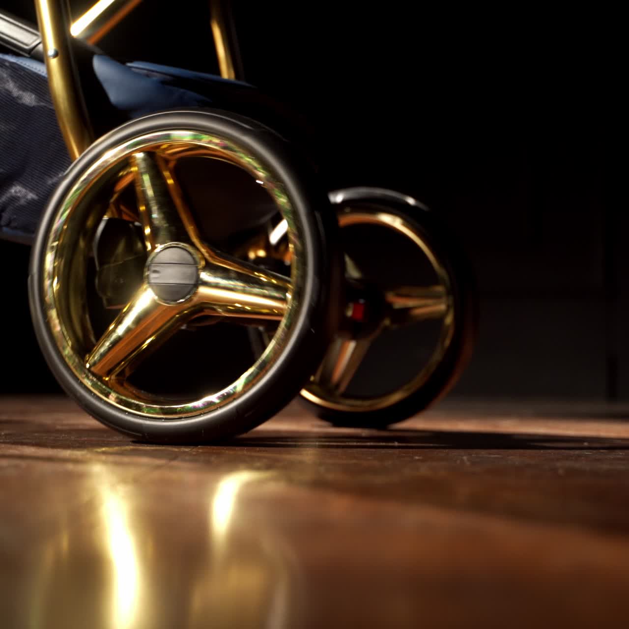 Unrecognizable woman pushes baby pram. Lower part of a child vehicle with shining details. Dark backdrop