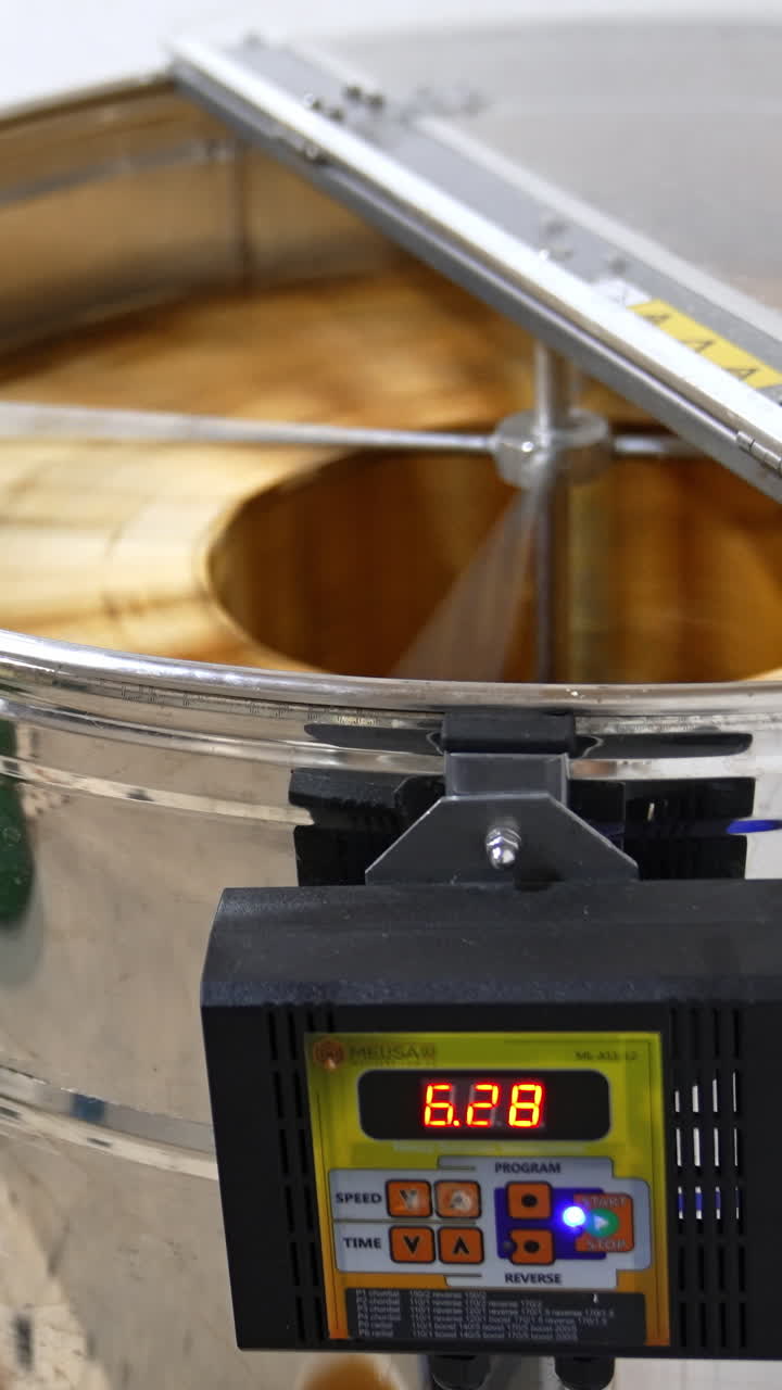 Metal electronic centrifuge device rotating the wooden frames with honeycombs. Extraction of organic honey at apiary. Vertical video