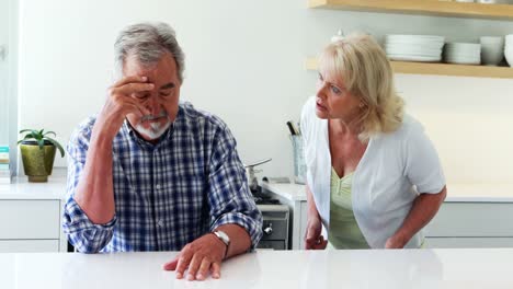unhappy senior couple arguing in kitchen