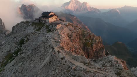 lone hiker at mountain hut nuvolau on mountain peak, during sunset in the dolomites, cinque torri