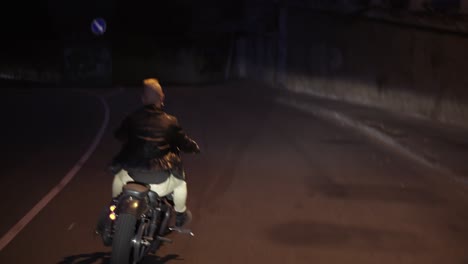 Rare-view-of-a-man-riding-on-a-motorcycle-on-a-turn-clings-to-the-asphalt,-sparks-fly-at-night