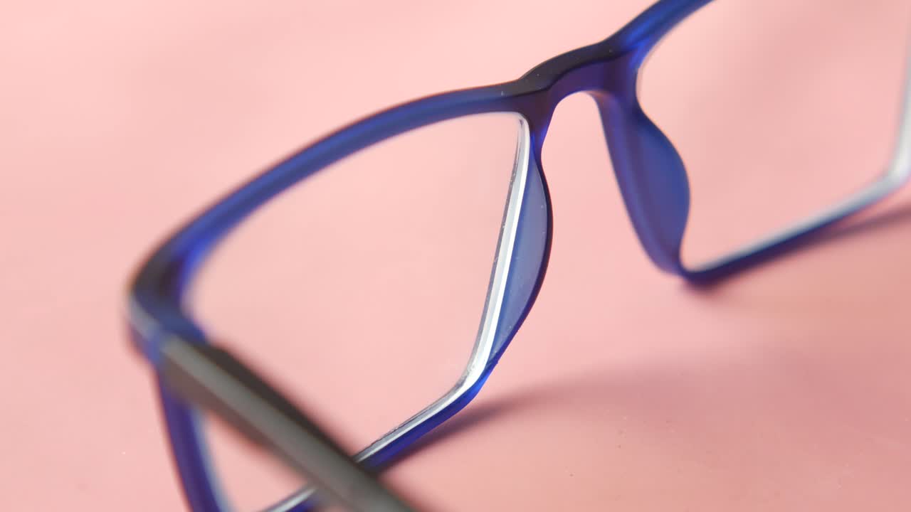 primer plano de gafas azules sobre un fondo rosado