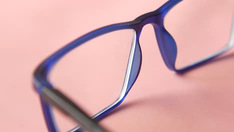 close-up of blue eyeglasses on pink background