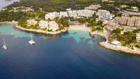 Playa-illetas-with-turquoise-water,-yachts,-and-resorts-under-sunny-skies,-aerial-view