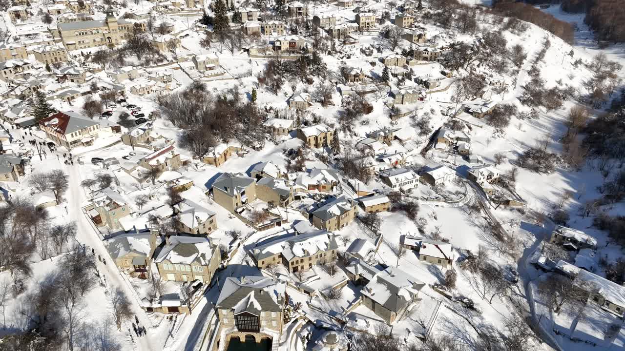 Tilt down aerial view of the city after a heavy snowfall with snow-covered roofs. Nymfaion, Florina, Greece.